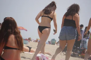 Sexy beach babe in yellow and blue bikini with friends