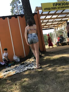 Young Skinny Girl Taking Off Her Denim Shorts Leaving a Swimsuit - Bending Over While Laying a Blanket on the Ground at a Lake Nature Park Gallery
