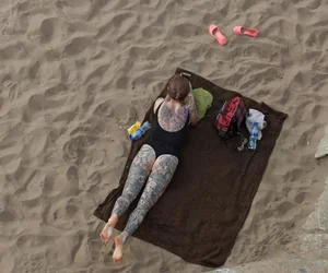Chubby Girl in Body Swimsuit Covered With Tattoos Lying on the Beach