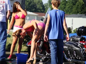Group of cute girls at a car wash in bikinis and shorts