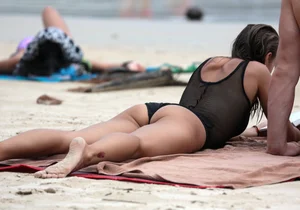 Skinny sexy lady on the beach in a black swimsuit