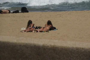 Two babes laying on the beach in bikinis with nice asses