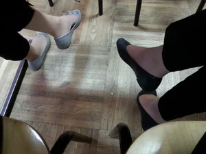 Crossed Legs of Two Student Girls Under Desk, Feet in Pantyhose And Flats
