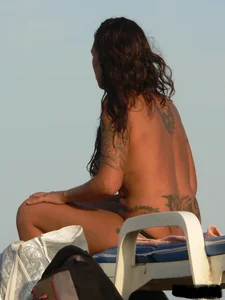 Topless tattooed lady on the beach with fake big tits
