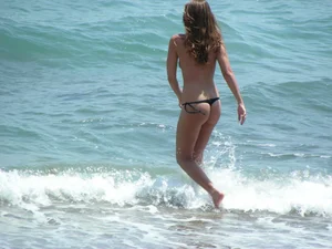 Topless girl with tan lined tits and in a black thong bikini
