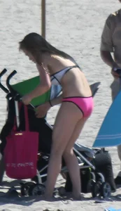 Skinny blonde girl on the beach in her pink and white bikini