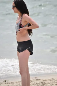 Brunette girl in black shorts and bikini top on the beach