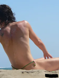 Topless beach milf looking sexy in a tiny g-string bikini