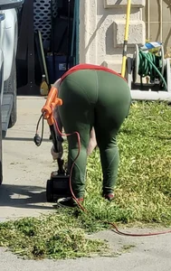 Mature milf in green yoga pants bending over while mowing lawn