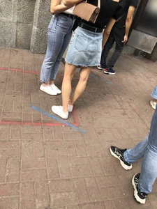Hot slim legs closeups, street girl wearing a denim fringed skirt