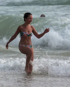 Cute skinny girl in a bikini at the beach playing in the water