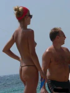 Topless skinny blonde lady in a g-string bikini at the beach