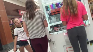 Little blonde teen in grey leggings at the mall with her friends
