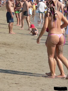Topless tattooed lady at the beach with a nice ass in pink thong bikini