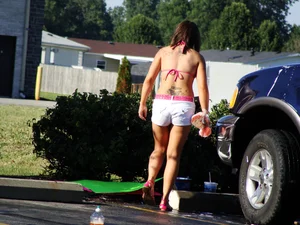 Group of cute girls at a car wash in bikinis and shorts
