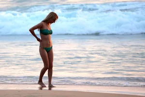 Sexy brunette in thong bikini and blonde friend in green bikini at the beach