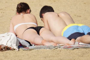 Sexy girl on the beach laying out and bending over in her bikini