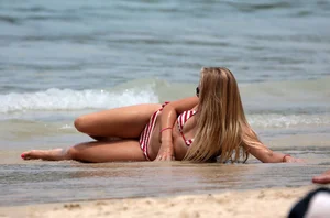 Blonde looking sexy on the beach in red striped bikini