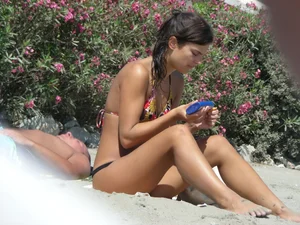 Sexy girl on the beach getting some sun in a little black thong bikini