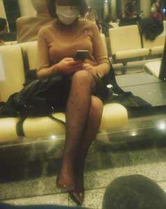 Girl in a Mask And Black Pantyhose With Dots Sitting With Crossed Legs at a Station