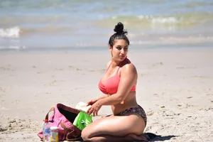 Huge boobed thick brunette babe on the beach in a bikini