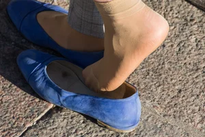 Feet in transparent short socks and flats closeups on the street: candid girl taking off her shoe and plating with her foot in public