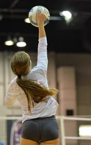 Skinny girl jumping while playing volleyball
