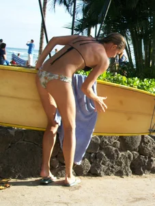 Skinny blonde surfer on the beach in little bikini