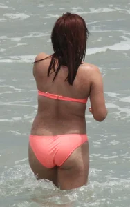 Thick girl in orange bikini playing on the beach