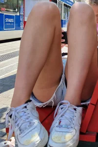 Girl in mini shorts lying on a bench at the bus stop