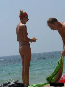 Topless skinny blonde lady in a g-string bikini at the beach