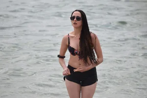Brunette girl in black shorts and bikini top on the beach