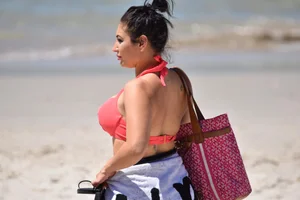 Huge boobed thick brunette babe on the beach in a bikini