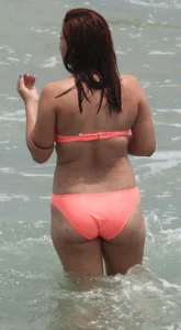 Thick girl in orange bikini playing on the beach