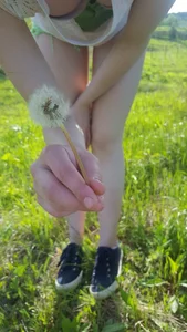 Cute Teen in a Blouse Holding a Dandelion Sitting in the Green Field