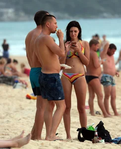Sexy brunette in thong bikini and blonde friend in green bikini at the beach
