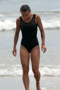 Skinny sexy lady on the beach in a black swimsuit