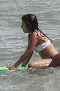 Brunette bikini girl on the beach and surfing in her bikini