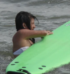 Brunette bikini girl on the beach and surfing in her bikini