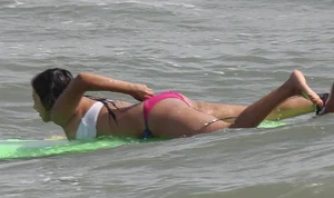 Brunette bikini girl on the beach and surfing in her bikini