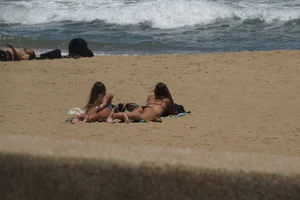Two babes laying on the beach in bikinis with nice asses