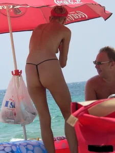 Topless skinny blonde lady in a g-string bikini at the beach