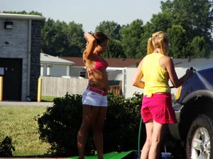 Group of cute girls at a car wash in bikinis and shorts