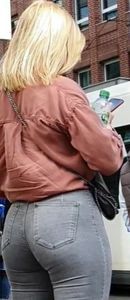 Blond girl in tight grey jeans waiting for the bus