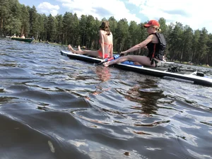 Skinny Girls in Swimsuits Sitting on a Board on a Lake