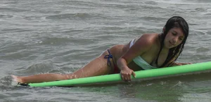 Brunette bikini girl on the beach and surfing in her bikini