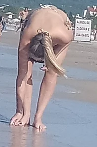 Smooth bodied and sexy blonde at the beach in a thong bikini