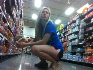 Cute candid blonde wearing shorts squatting at the supermarket