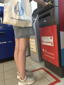 Young Candid Girl With Slim Pale Legs In a Denim Skirt Waiting in the Queue