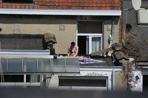 Neighbor on rooftop tanning in bikinis